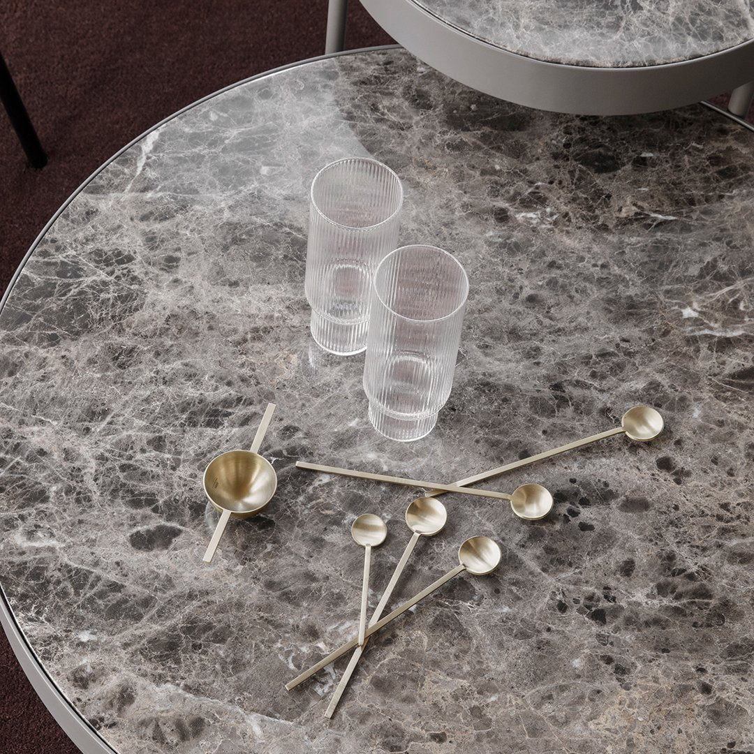 "Elegant grey marble table with clear glass and gold-accented spoons, featuring a modern, stylish design."