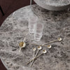 "Elegant grey marble table with clear glass and gold-accented spoons, featuring a modern, stylish design."