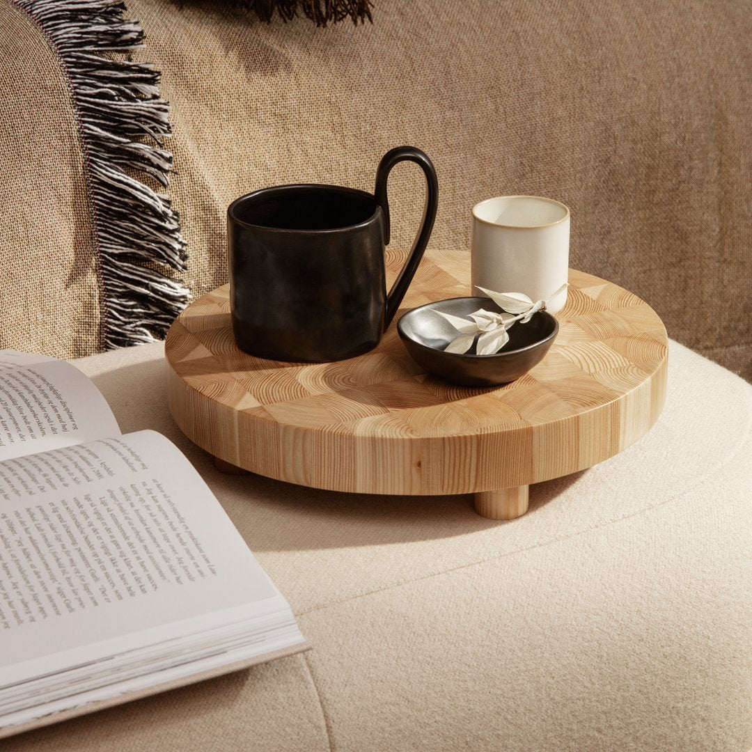 "Round wooden tray with a natural bamboo finish, featuring a black cup and white candle against a soft, neutral background."