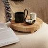 "Round wooden tray with a natural bamboo finish, featuring a black cup and white candle against a soft, neutral background."