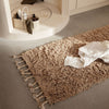 Tan shag rug with tassels, featuring a soft, textured surface ideal for cozy interiors.
