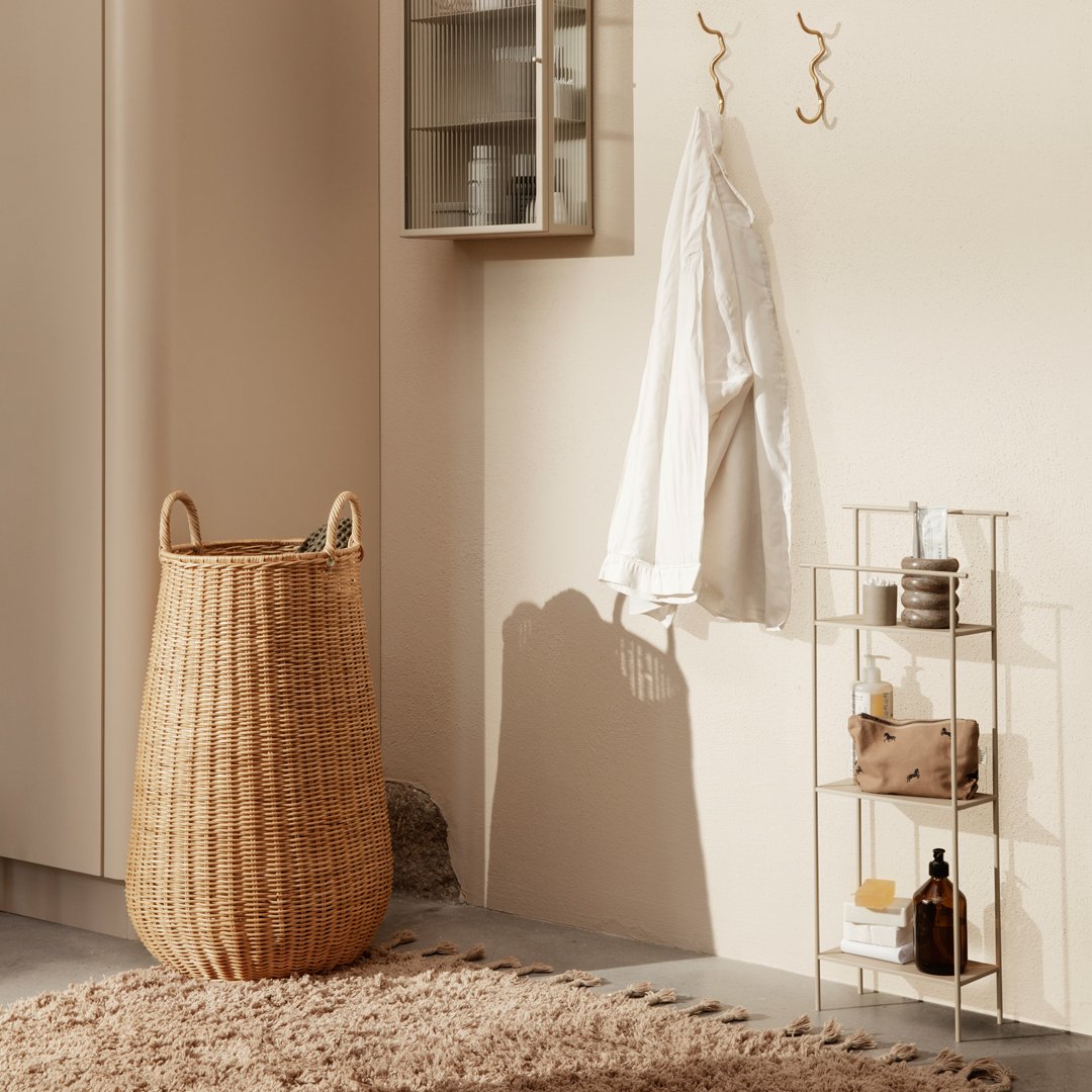 Natural woven basket in beige, gold accents, soft white coat, and earthy tones in a minimalistic interior setting.