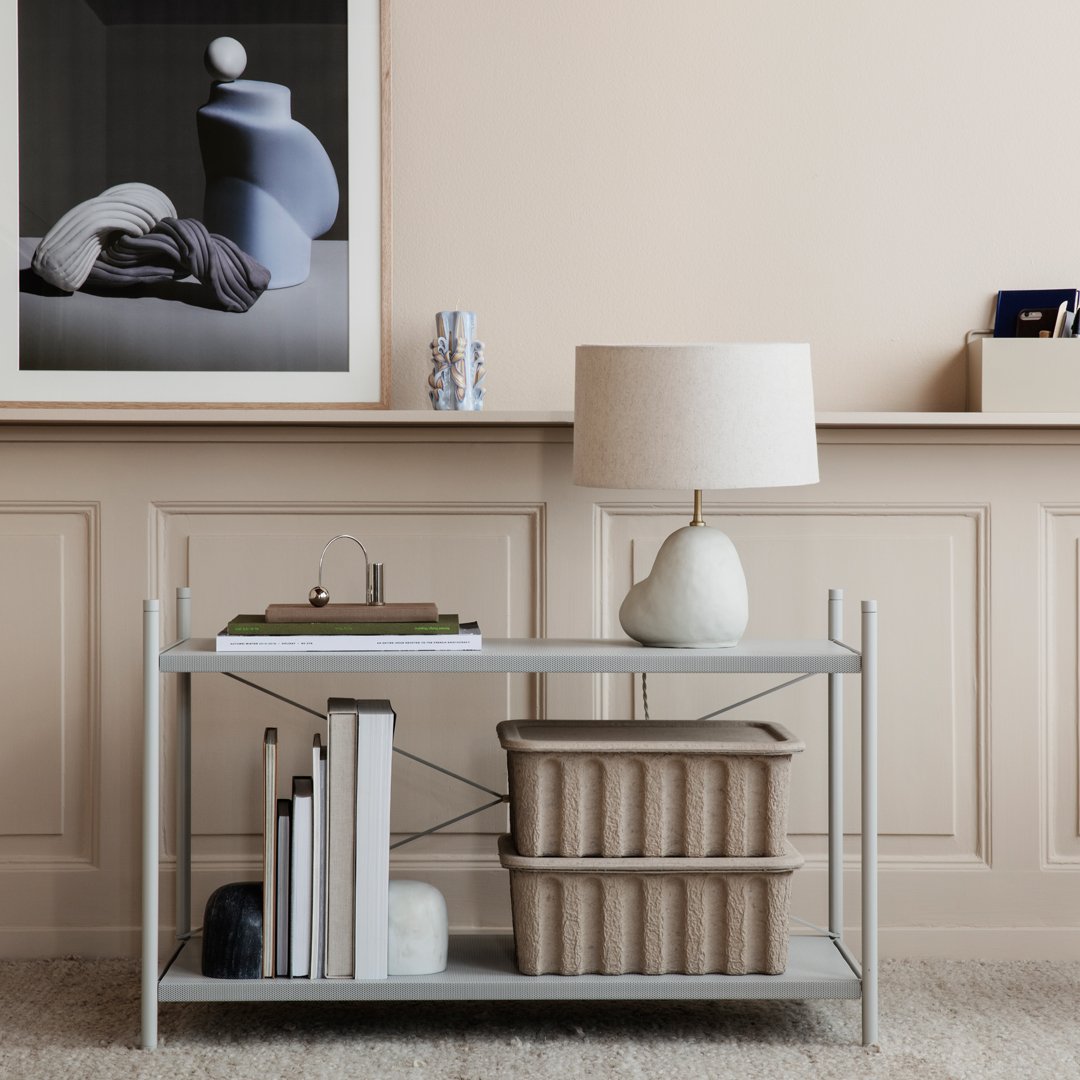 Modern light gray console table with a minimalist design, featuring textured beige storage bins and soft pastel accents.