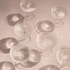 Elegant clear glass dessert bowls with intricate patterns and soft shadows on a pastel surface.
