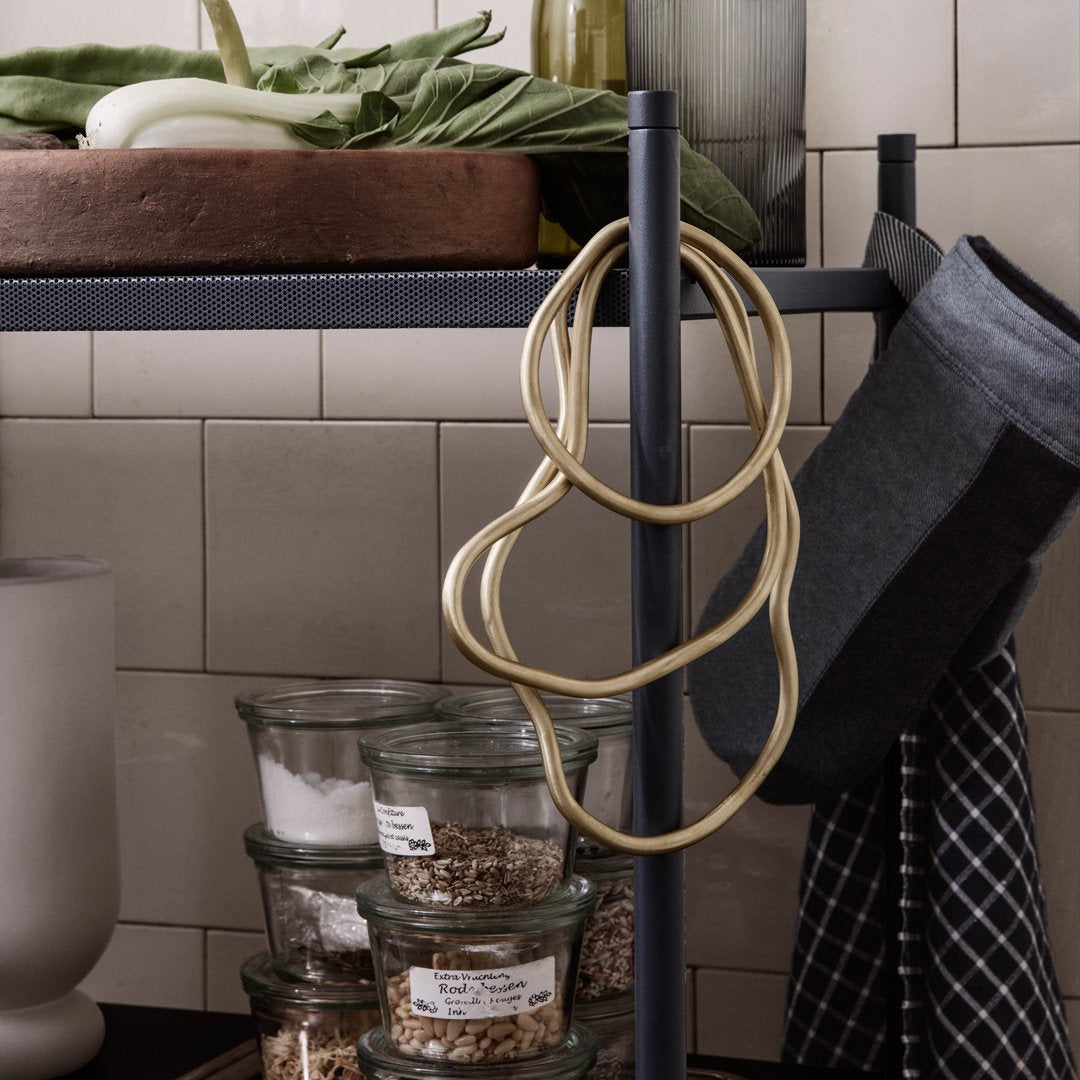"Neutral-toned kitchen accessories with natural beige cords and dark gray textiles against a clean, tiled backdrop."