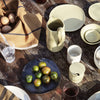 "Earthy tones with olive green, ivory, and dark slate blue patterns on rustic tableware, featuring elegant textures."