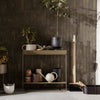 Stylish console table in earthy tones with neutral ceramics and greenery against a textured dark wall.