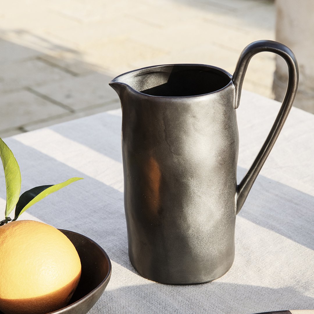 Black ceramic pitcher with a smooth, matte finish and organic shape, perfect for modern table settings.