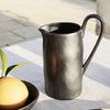 Black ceramic pitcher with a smooth, matte finish and organic shape, perfect for modern table settings.