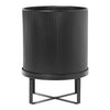 Black ribbed planter with a sleek metal stand, featuring a modern minimalist design. Vibrant and stylish decor piece.