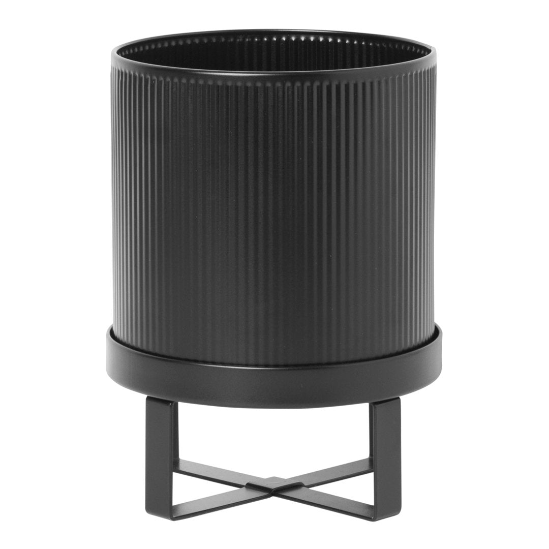 Black ribbed planter with a sleek metal stand, featuring a minimalist design and modern aesthetic.