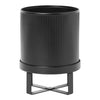 Black ribbed planter with a sleek metal stand, featuring a minimalist design and modern aesthetic.