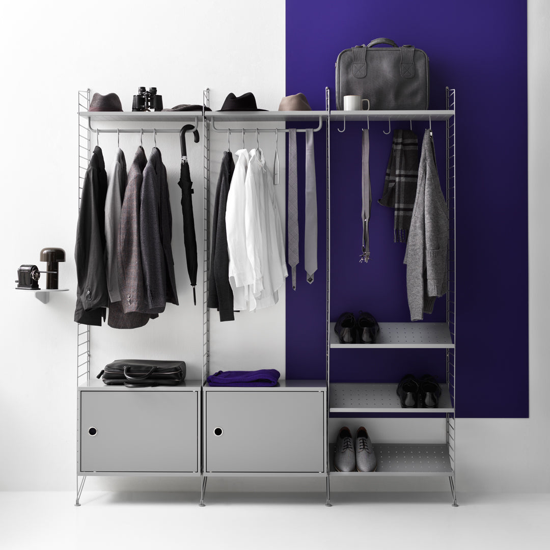 "Gray clothing rack with assorted garments, purple wall backdrop, and silver storage bins for a modern look."
