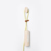 Wooden cord organizer with light yellow cord and brown leather accent against a clean white background.