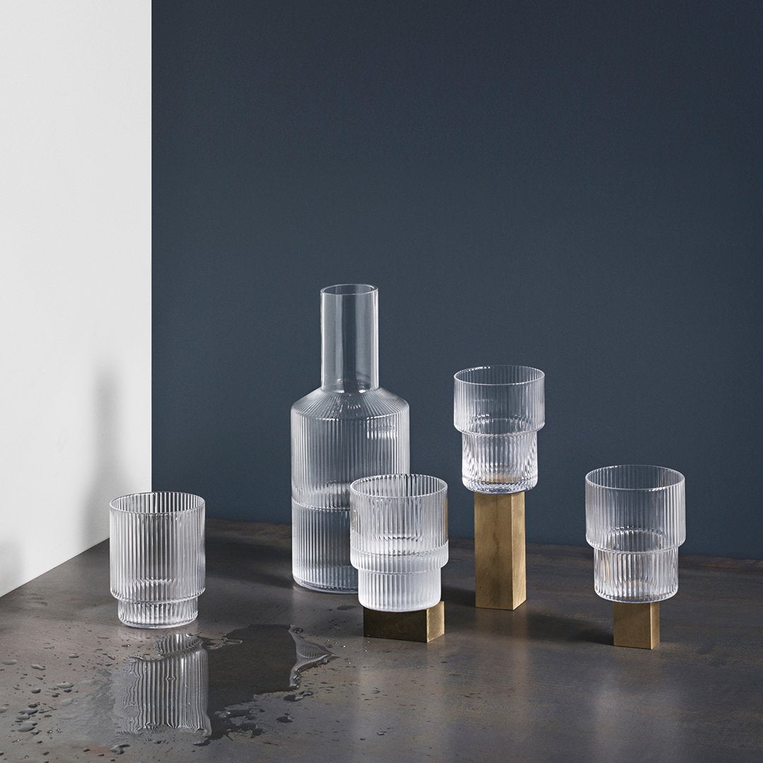 Elegant frosted glassware set with brass accents, featuring clear and matte textures against a dark background.