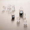 Clear glass drinkware set featuring a sleek carafe and various shot glasses with rich dark liquid.