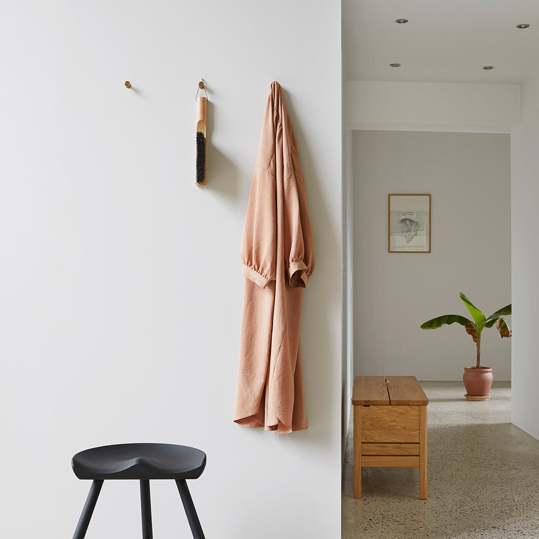"Soft terracotta robe hangs against a neutral wall, complemented by minimalist black and wooden decor accents."