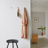 "Soft terracotta robe hangs against a neutral wall, complemented by minimalist black and wooden decor accents."