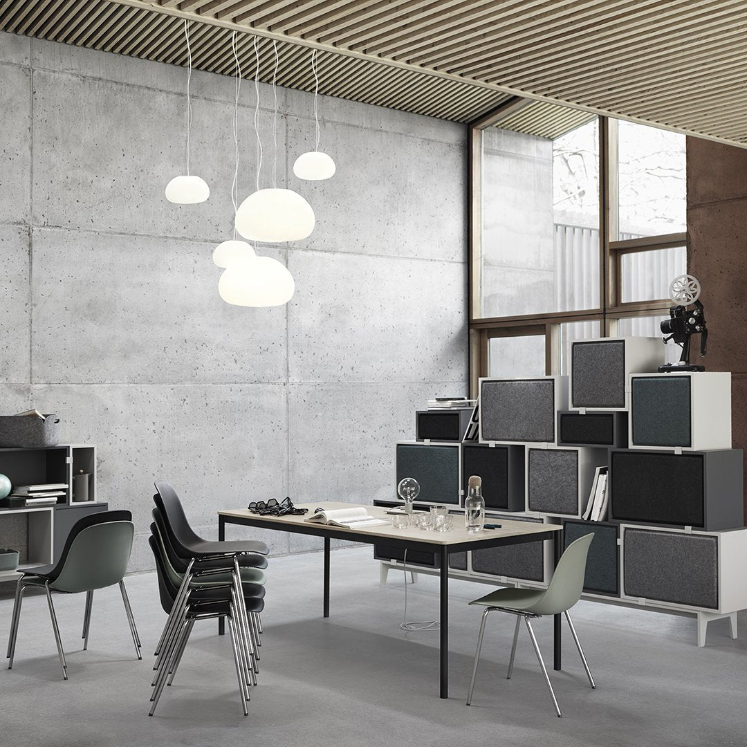Modern workspace with grey concrete walls, white pendant lights, and black and white furniture accents.