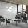 Modern workspace with grey concrete walls, white pendant lights, and black and white furniture accents.