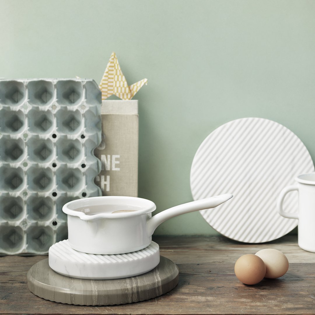 White cookware on textured white and gray surfaces, featuring subtle patterns and soft pastel green background.