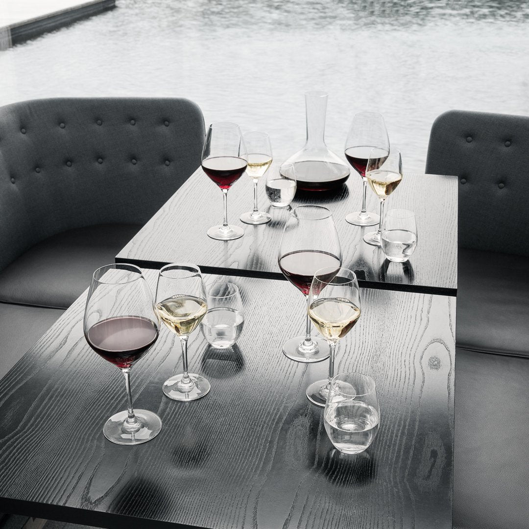"Elegant glassware set featuring rich reds and yellows atop a dark wood table, with a sleek, modern grey backdrop."