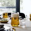 Clear glass beer and shot glasses filled with golden beer and colorless liquid, surrounded by a neutral table setting.