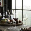 Elegant glassware featuring red, white, and rosé wines beside a rustic wooden table with green and earthy tones.