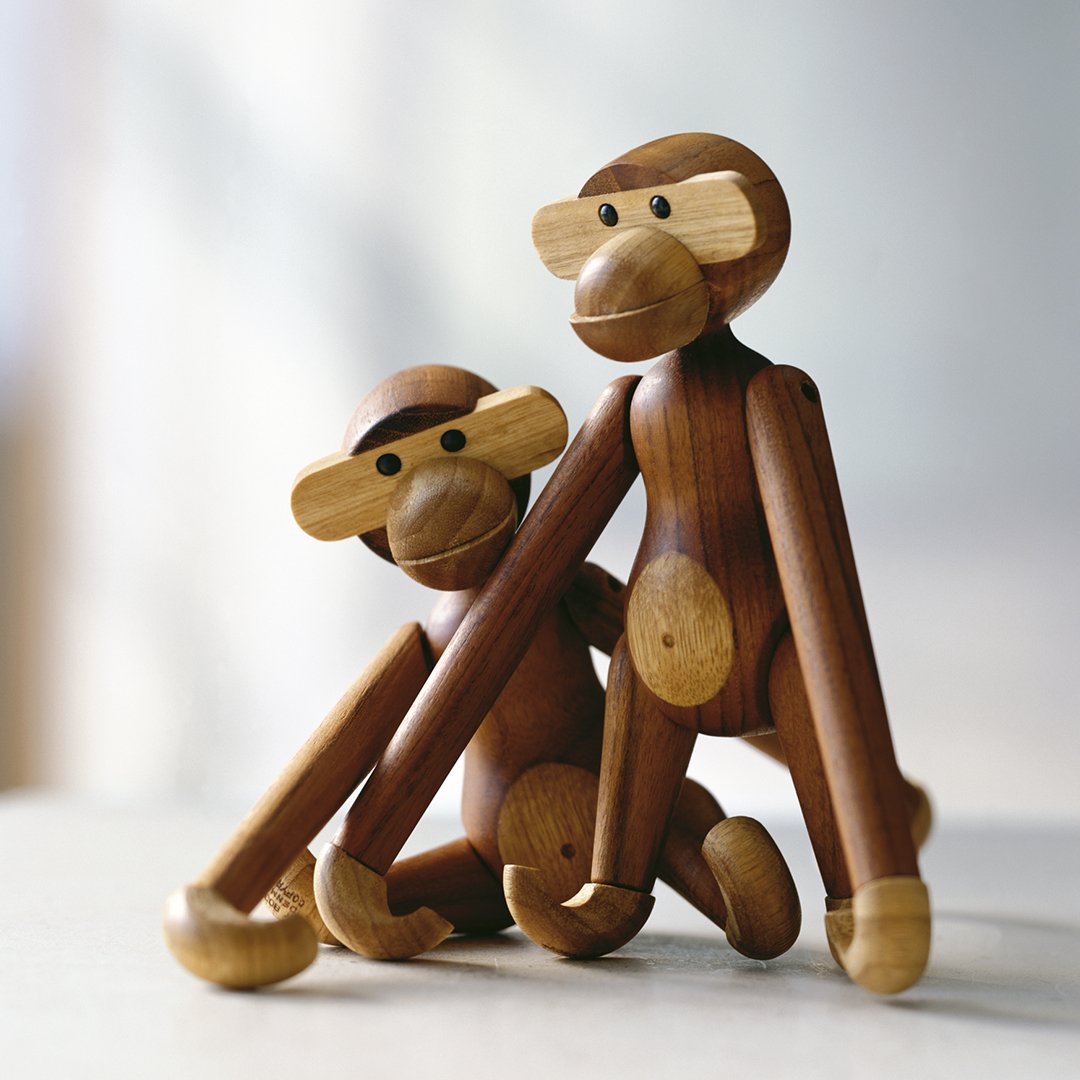 Two wooden monkey figurines in rich brown tones with natural wood accents, showcasing a minimalist design.