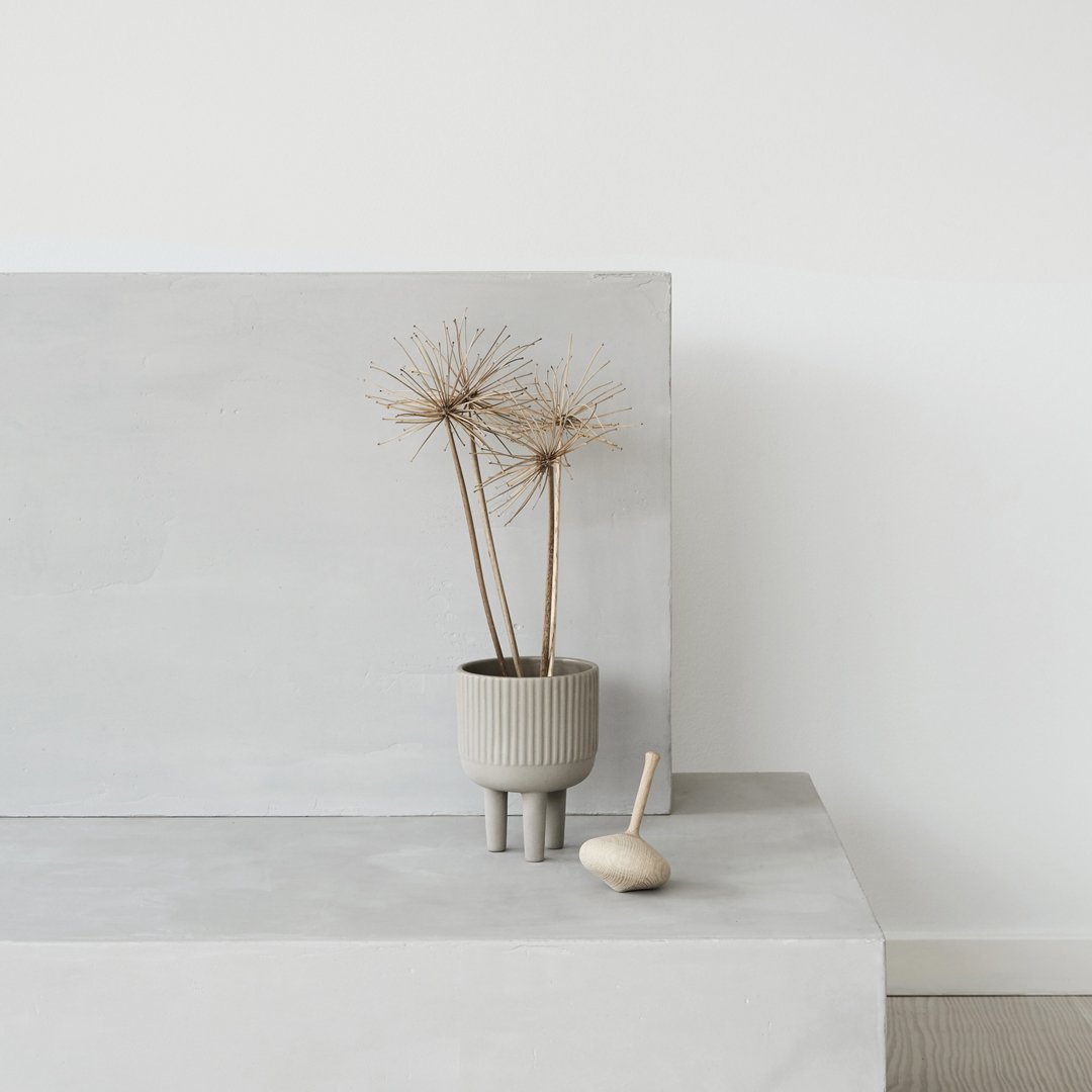 Grey decorative vase with dried plants, minimalist design on a smooth concrete surface. Modern and stylish home decor.