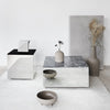 Elegant gray and black tables with smooth surfaces, complemented by neutral vases and earthy tones in a minimalist setting.