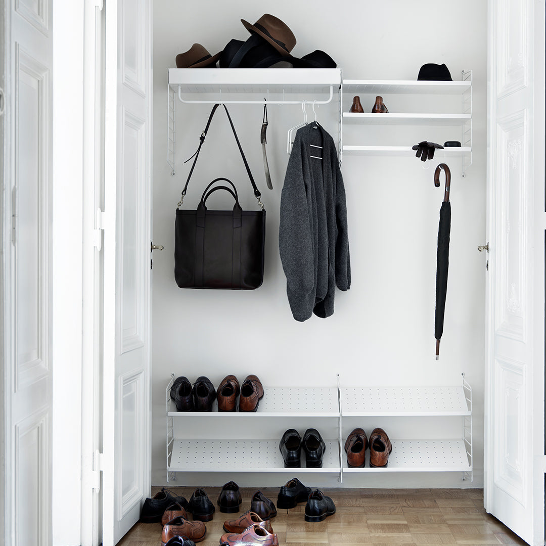 White closet with gray clothing and black accessories, featuring a sleek, minimalist design with organized shoes below.
