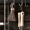 Natural brown broom with wooden handles, displayed against a rustic wooden backdrop. Subtle textures and earthy tones.