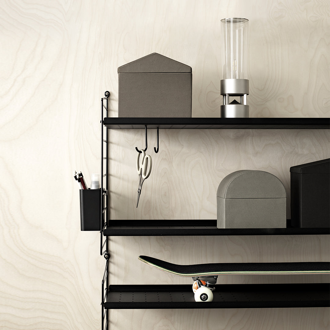 Black shelving unit featuring geometric gray storage boxes with a minimalist design against a textured beige wall.