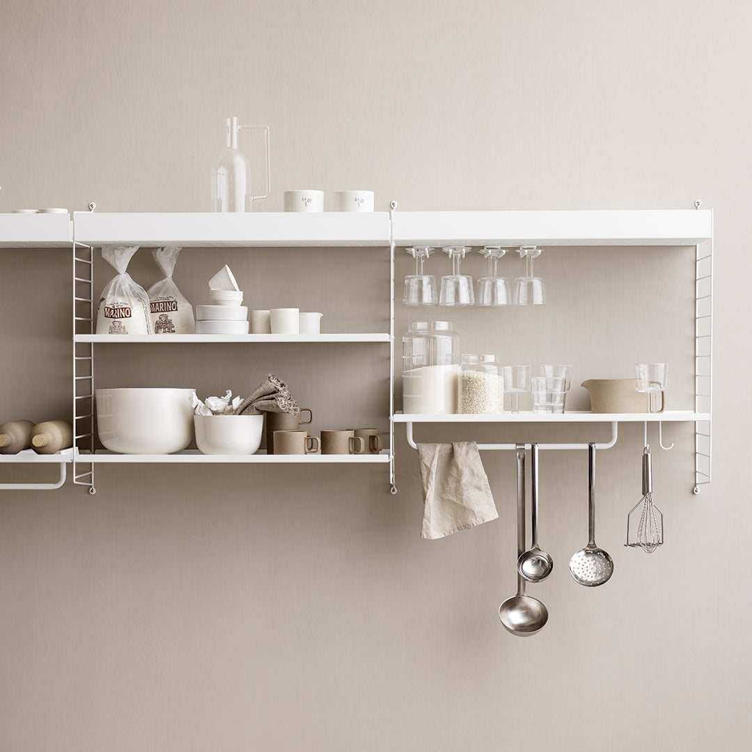 White shelves with minimalist design, featuring glassware and ceramic dishes in soft neutrals and subtle textures.