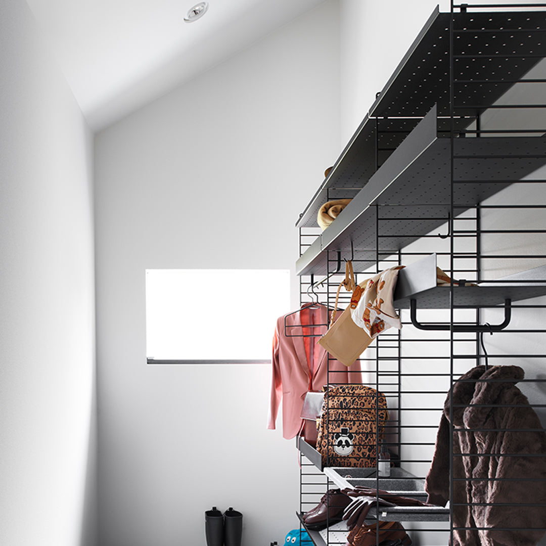 "Stylish black shelving with a mix of pastel pink, earthy brown, and patterned fabrics in a minimalist setting."