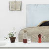 Colorful glassware on a neutral background, featuring red, clear, and earthy tones with green plant accents.