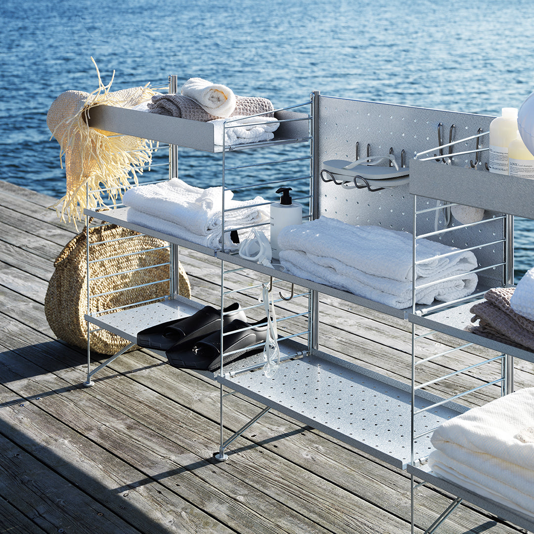 "Stylish white towels and accessories on a modern silver metal rack against a serene blue water backdrop."