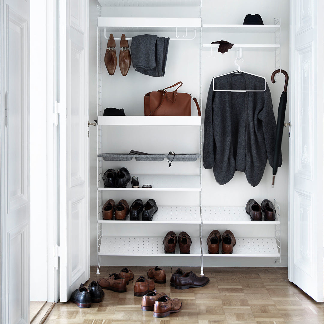 Interior closet in white featuring black clothing, brown leather shoes, and tan accessories arranged neatly.