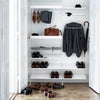 Interior closet in white featuring black clothing, brown leather shoes, and tan accessories arranged neatly.