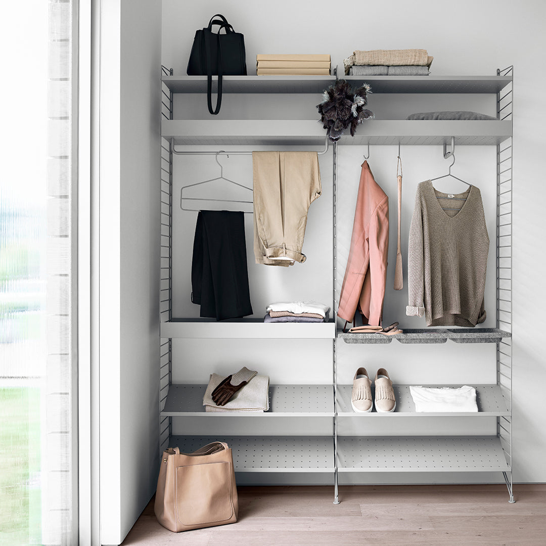 Gray shelving unit with a minimalist design, featuring light-toned clothing and accessories in pastel colors.
