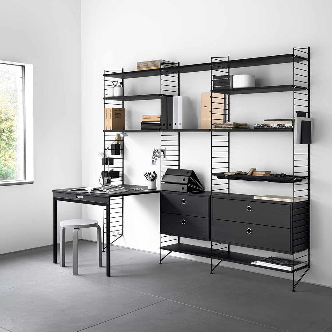 "Modern black metal shelving unit with a minimalist desk and grey floor, featuring clean lines and geometric patterns."