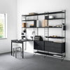 Black metal shelving unit against a white wall, with a matching black desk and gray floor, featuring minimalist design.