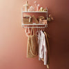 Stylish wall shelf displaying soft pink and neutral tones with a patterned golden bag and clothing items.