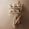 White shelving unit displaying neutral tones and organic textures, featuring woven bags and ceramic dishware.