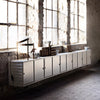 Sleek white storage cabinet with minimalist design, showcasing clean lines against rustic brick walls and natural light.
