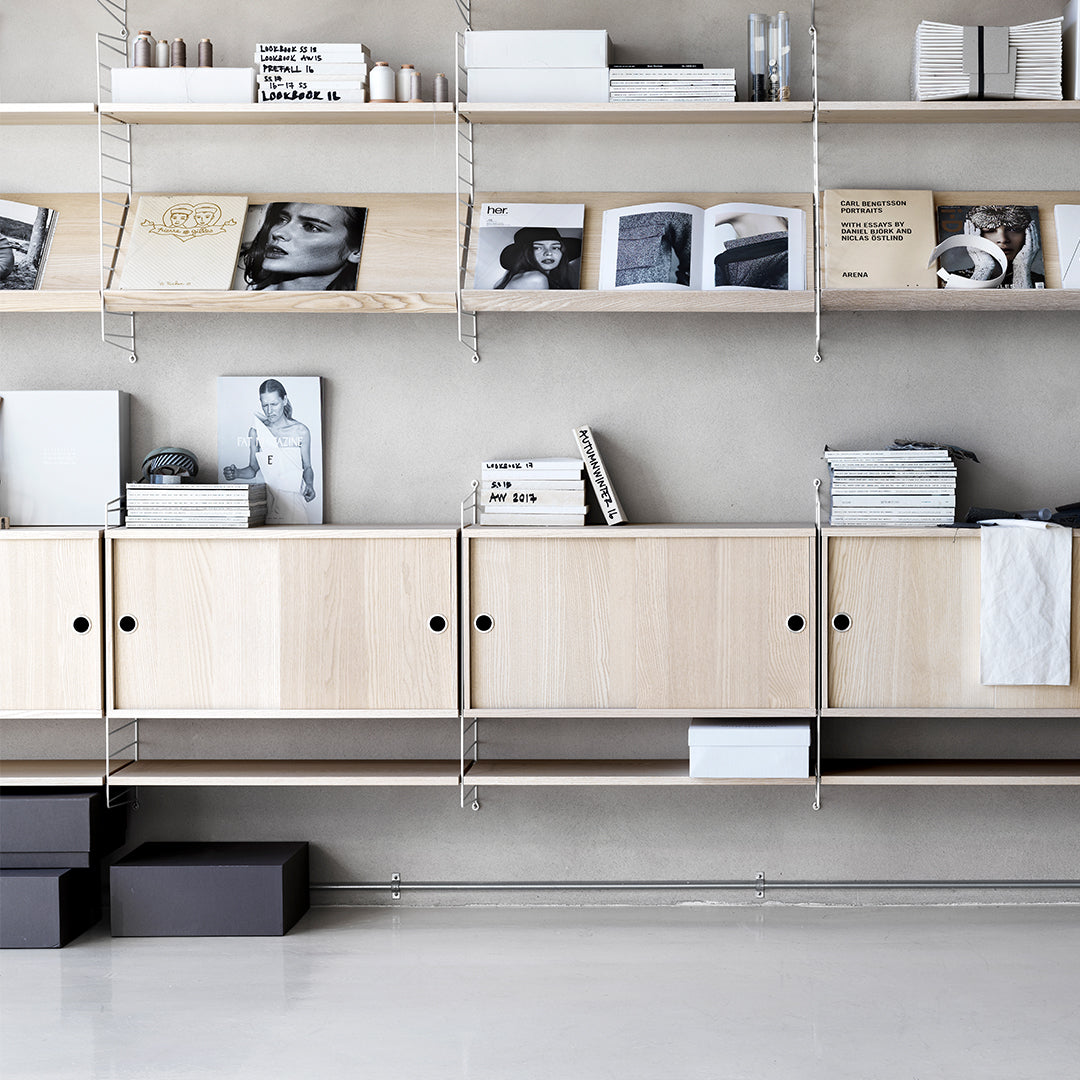 Minimalist wooden shelves in natural tones with black accents and white items, featuring a sleek, modern design.