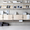 Minimalist wooden shelves in natural tones with black accents and white items, featuring a sleek, modern design.