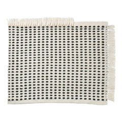 Woven cream placemat featuring a black square pattern with fringed edges for a chic, modern look.