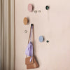 Colorful wall hooks in pink, orange, blue, green, and silver display against a soft beige background.